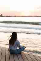 Free photo back view woman meditating outdoors