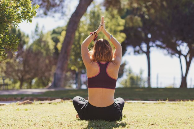 Back view woman meditating in park