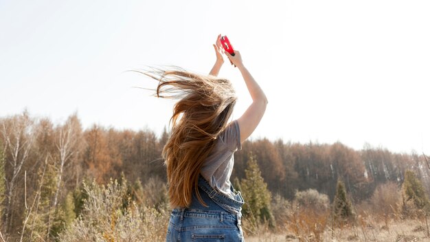 Back view of woman in nature holding tambourine