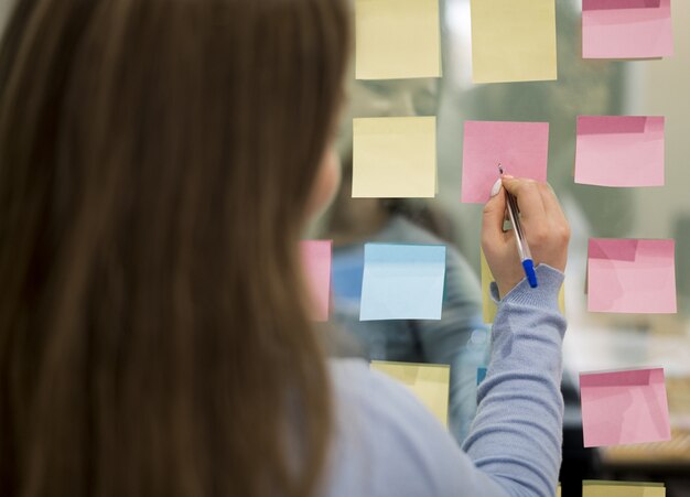 Back view of woman in office writing on sticky notes