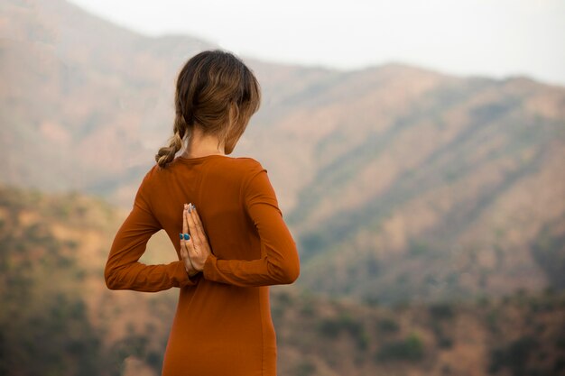 Back view of woman outdoors in nature in yoga pose with copy space