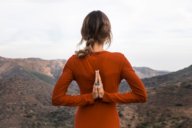 Back view of woman outdoors in nature in yoga pose