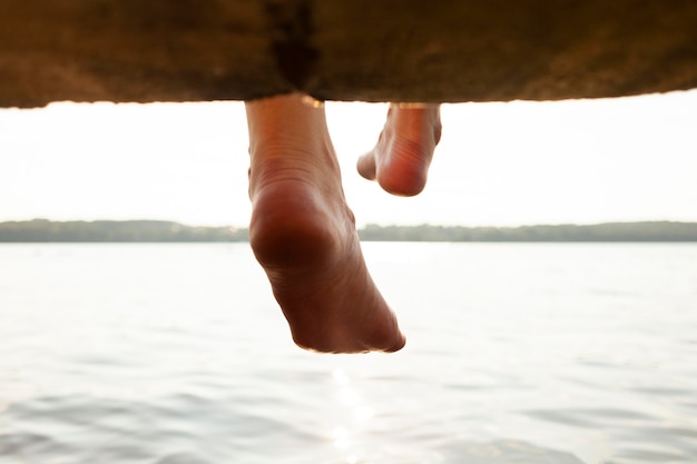 Free photo back view of woman playing with lake water and feet