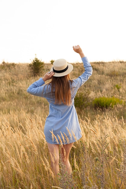 Back view of woman posing in the fields with hat