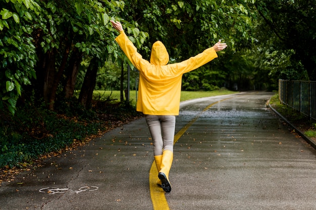 Foto gratuita vista posteriore donna in cappotto di pioggia