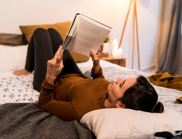 Free photo back view woman reading a book in bed