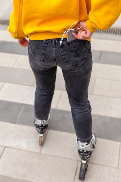 Free photo back view of woman in roller blades with smartphone