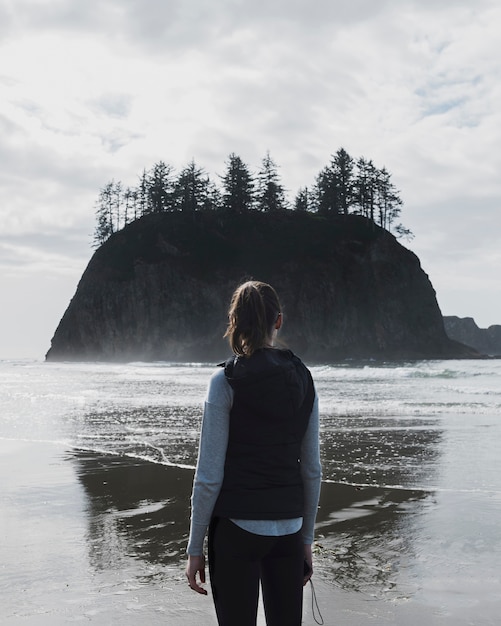 Back view of woman on shore with cliff