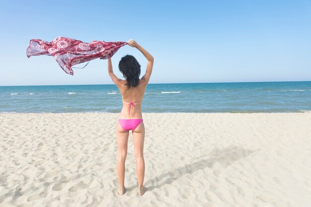 海を見てビーチに立っている背面図女性