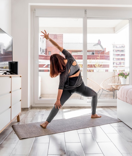 Back view woman stretching indoors