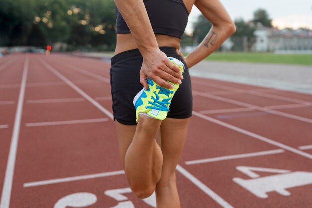 Free photo back view woman stretching on running track