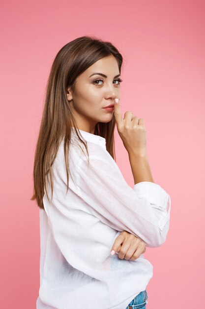 Back view of woman in summer look on pink wall