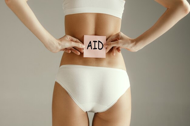 Back view of woman taking word AID isolated on gray wall