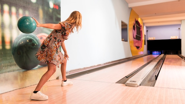 Back view woman throwing bowling ball