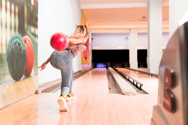 Back view woman throwing bowling ball