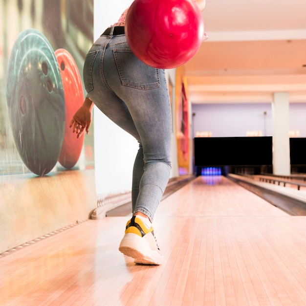 Free photo back view woman throwing bowling ball