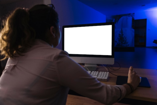 Женщина с задним взглядом, используя компьютер в ночное время