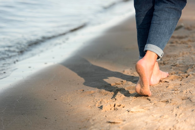 Back view of woman walking barefoot on the beach