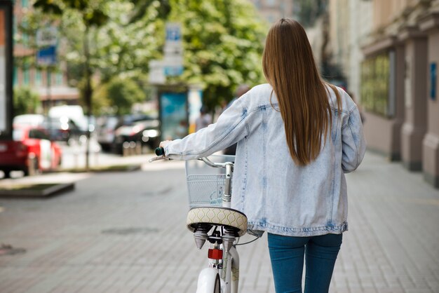 自転車の横に歩く背面図女性