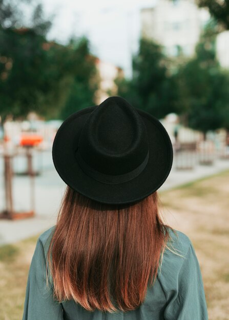 秋に黒い帽子をかぶっている背面図女性