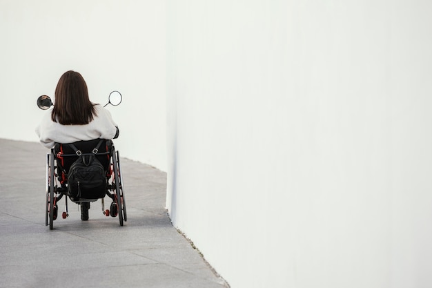Free photo back view of woman in a wheelchair with copy space