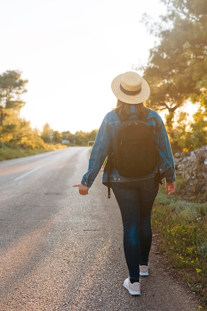 Back view of woman with backpack hitchhiking