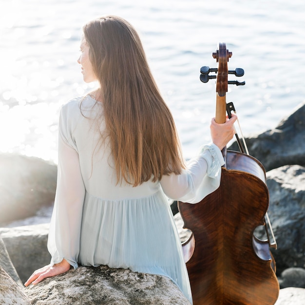 Back view of woman with cello by the sea