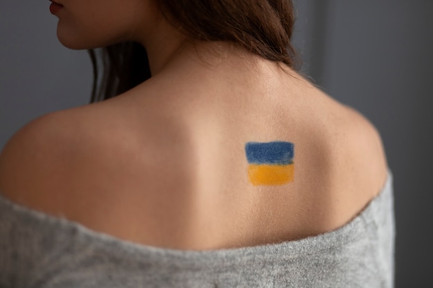 Back view woman with painted ukrainian flag