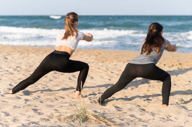 Back view of women exercising on the beach