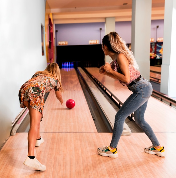 Free photo back view women playing bowling