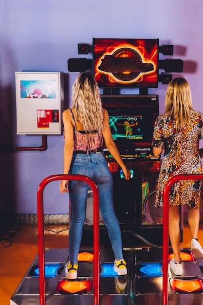 Vista posteriore donne che giocano a ballo arcade