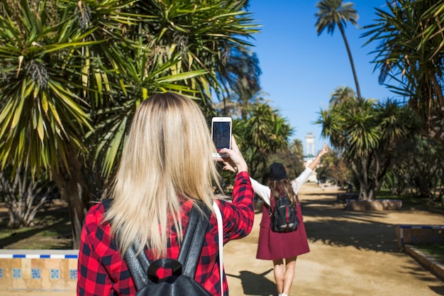 Back view women taking photos in park