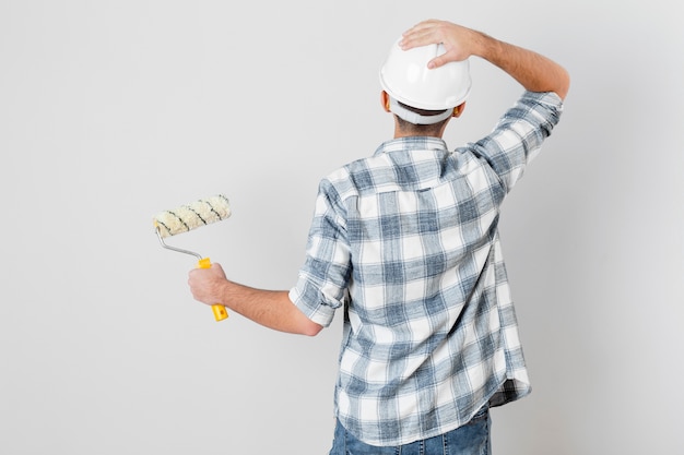 Free photo back view of worker holding a paint roller