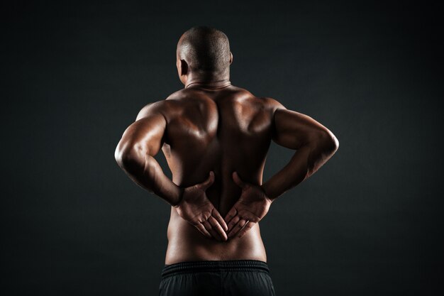 Back view of young african sports man feeling pain in his back