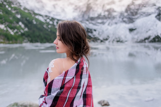 Free photo back view of young brunette girl in the winter mountains near the frozen lake