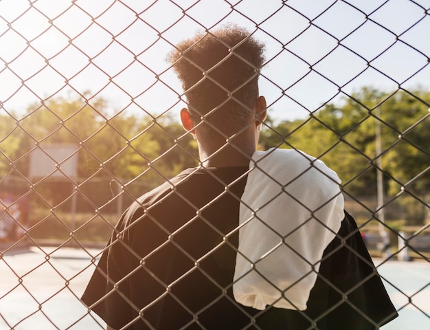 Free photo back view young man on a basketball field