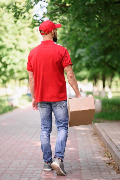 Free photo back view young man delivering cardboard box