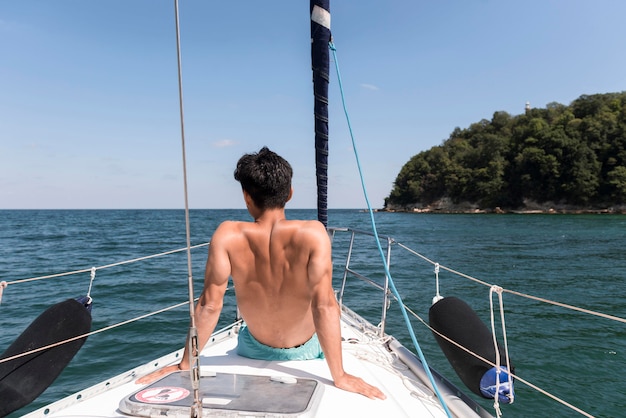 ボートで休暇を楽しんでいる若い男の背面図