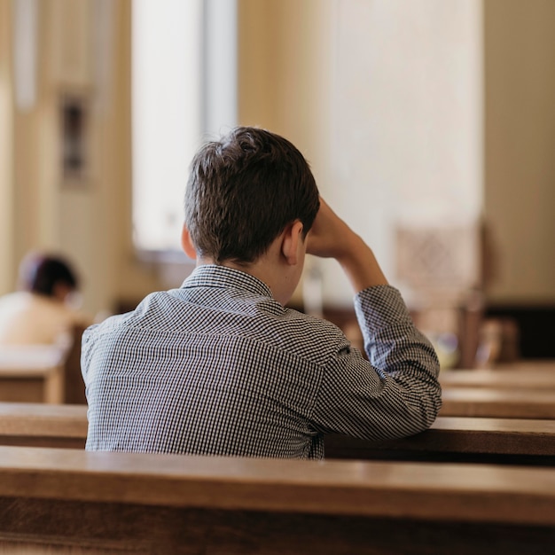 教会で祈っている若い男の背面図