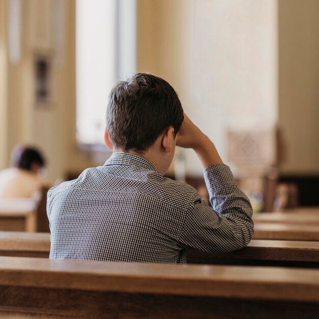 Back view young man praying in the church