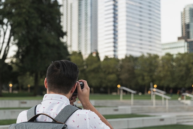 Free photo back view young man taking a picture