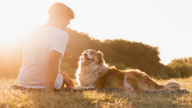 海辺で犬と一緒に若い男を背面図