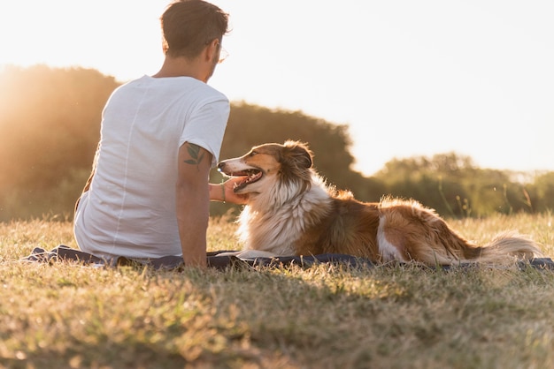 海辺で犬と一緒に若い男を背面図