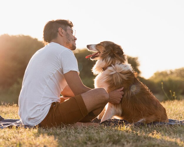 海辺で犬と一緒に若い男を背面図