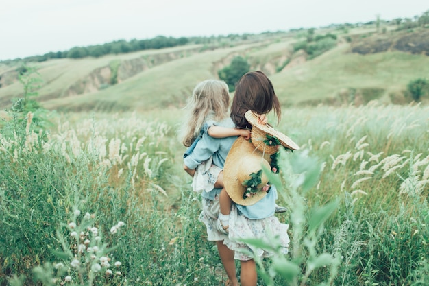 Free photo the back view of young mother and daughter on green grass.