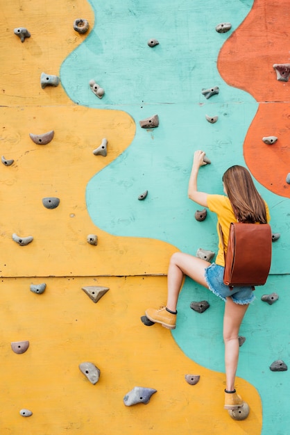 Back view young traveller climbing wall 