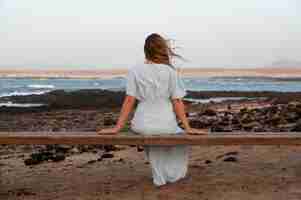 Foto gratuita vista posteriore giovane donna che guarda l'oceano