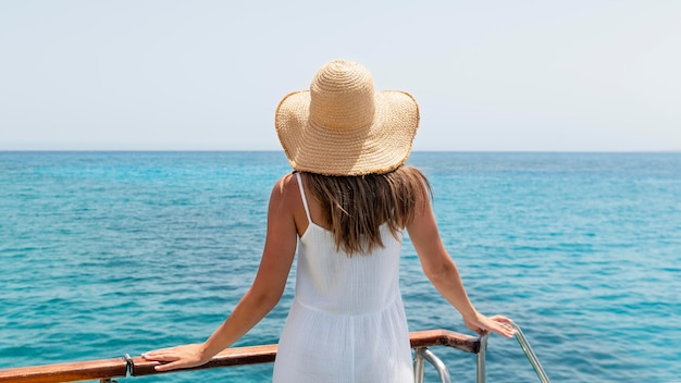 Free photo back view young woman looking at the ocean