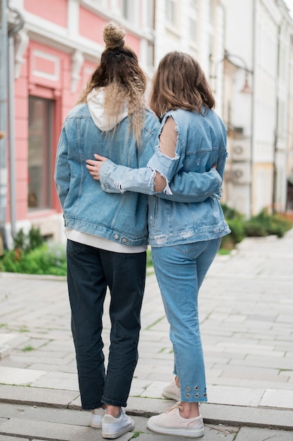 Free photo back view young women holding each other