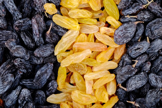 Background of dried fruits black and yellow raisins top view